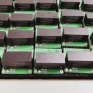 A group of black eletronic power convertor components on green circuit boards.