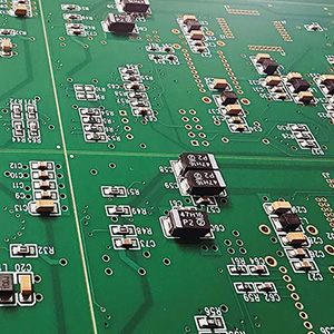 A close up of a green circuit board, small bland and silver electronic components with letters next to them scattered about.