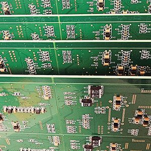 Green circuit boards stood up, four in a row. Each with various black and silver components.