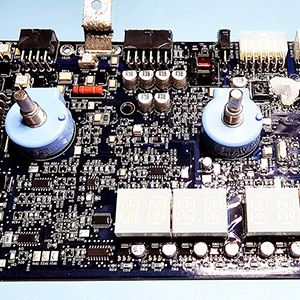 Blue circuit board with two blue knob components and segmented numerical display at the bottom.